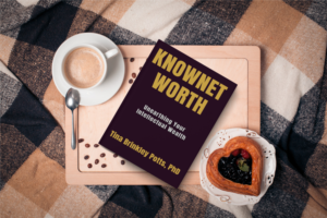 KnowNet Worth book with a cup of coffee on pink tablet